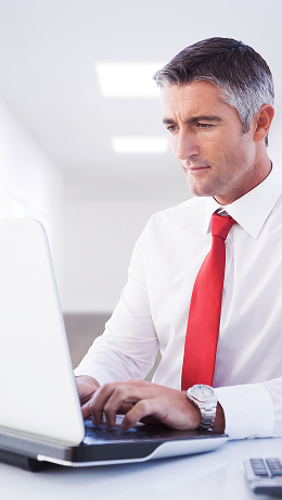 An attorney sits at a table, types on their laptop, and uses it to access their attorney portal