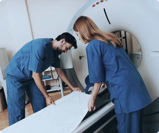 Los técnicos de radiología colocan sábanas limpias en una mesa deslizante en una máquina de tomografía computarizada