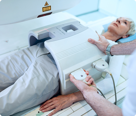 A technician adjusts MRI equipment for a patient who’s lying down and waiting for an abdominal MRI scan at an imaging center