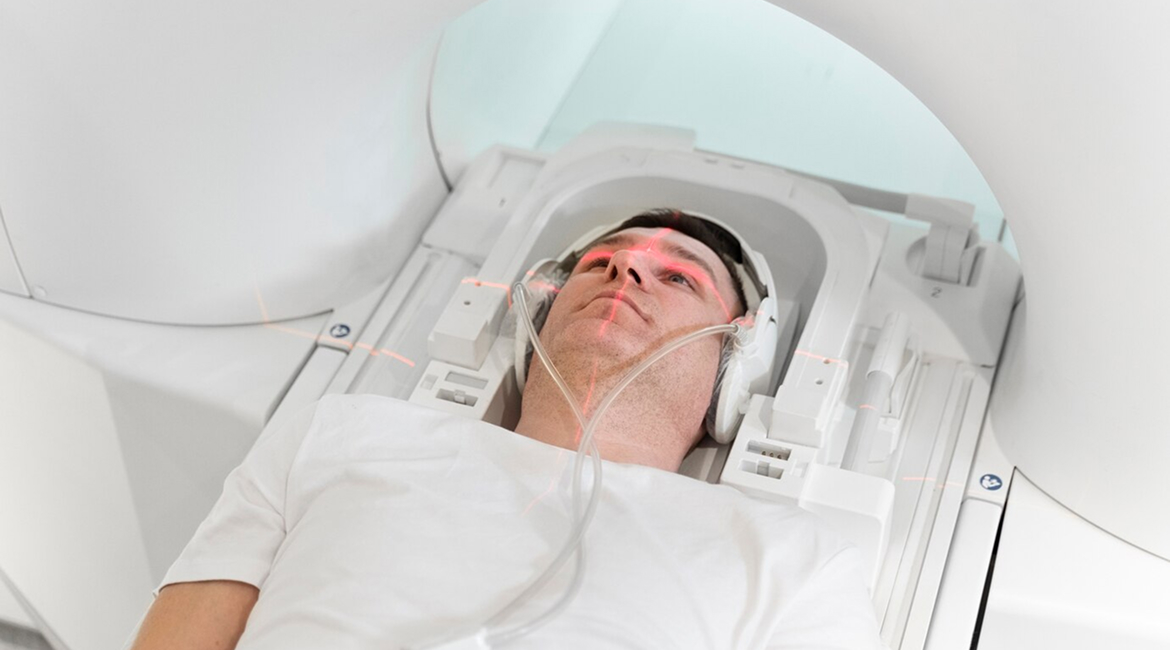 A patient is wearing headphones and lying down on a sliding table in an MRI machine at a diagnostic imaging center