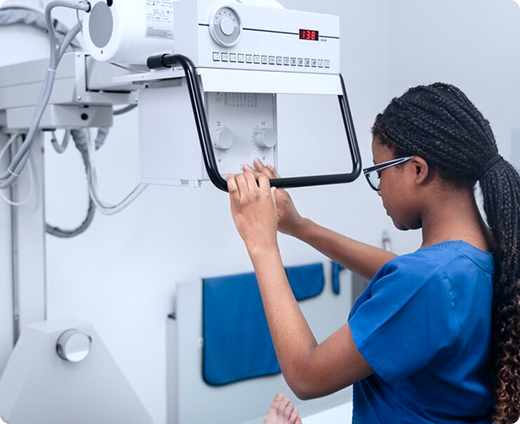 Una radiología prepara una máquina de rayos X para escanear la pierna de un paciente en un centro de imágenes