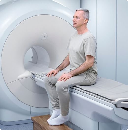 Un paciente se sienta en una mesa deslizante y espera su tomografía computarizada en un centro de MRI y diagnósticos Memorial