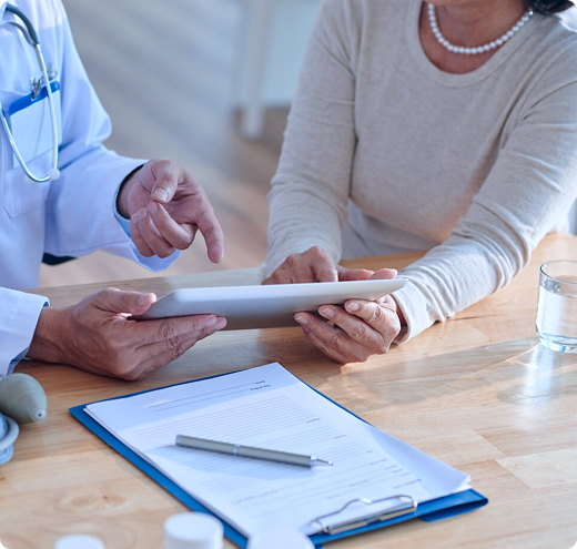 Un radiólogo se sienta junto a un paciente y analiza los resultados de las imágenes de diagnóstico en su tableta