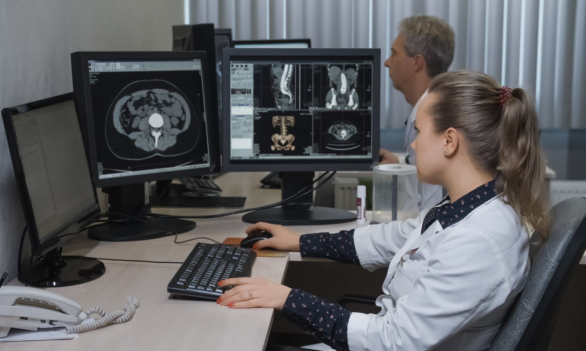 Radiologists sit at desks and look at images from MRI and CT scans on their computers