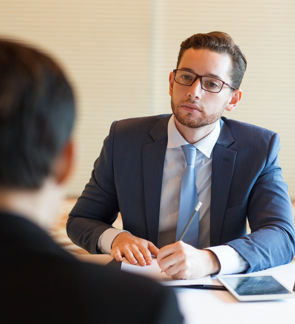 serious-manager-interviewing-applicant A medical professional, dressed in a suit and tie, sits in a conference room across from their patient