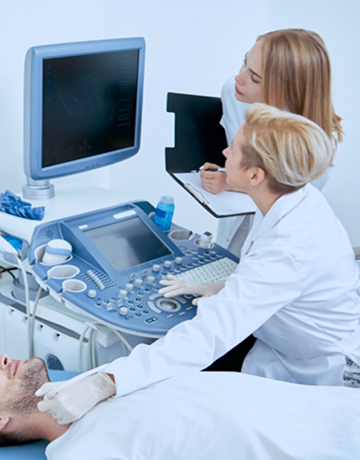 Radiologists watch imaging results on a screen while one radiologist moves a probe around a patient’s thyroid